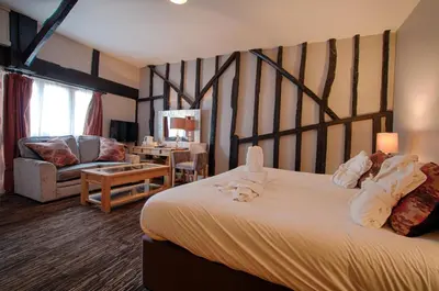 a bedroom with a large bed and a living room at The Saracens Head Hotel - The Coaching Inn Group in Great Dunmow