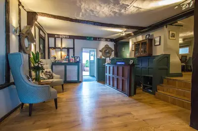 a living room with green cabinets and a staircase at The Saracens Head Hotel - The Coaching Inn Group in Great Dunmow