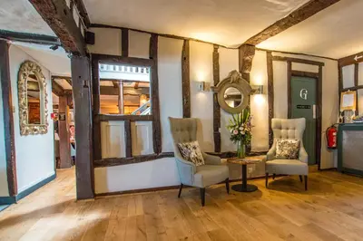 a room with two chairs and a table and a mirror at The Saracens Head Hotel - The Coaching Inn Group in Great Dunmow