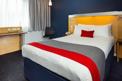 a hotel room with a large bed with a red pillow at Holiday Inn Express Cambridge by IHG in Cambridge