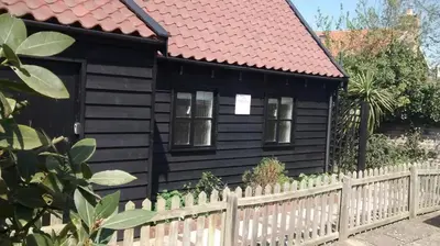 a black house with a white fence at Fox Inn in Darsham