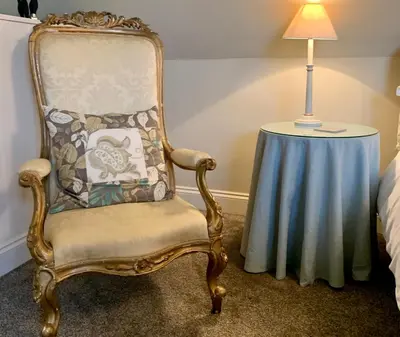 a chair sitting next to a table with a lamp at Fox Inn in Darsham