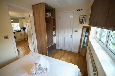 a bedroom with a bed with white sheets and a window at Fennec Apartments in Cherry Hinton