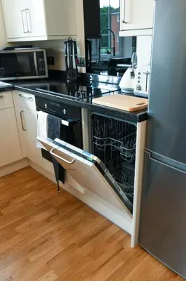 an empty dishwasher in a kitchen with a refrigerator at Fennec Apartments in Cherry Hinton