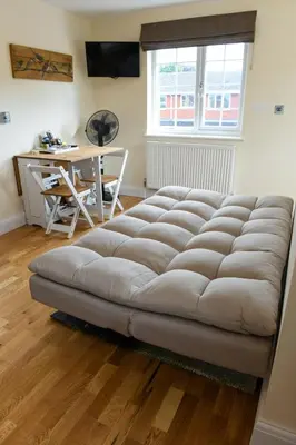 a large tufted couch in a room with a table at Fennec Apartments in Cherry Hinton