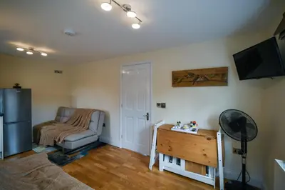a living room with a couch and a table and a refrigerator at Fennec Apartments in Cherry Hinton