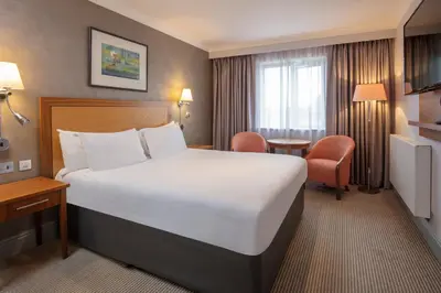 a hotel room with a large bed and a chair at Cambridge Belfry Hotel & Spa in Cambridge