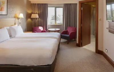 a hotel room with a large bed and a chair at Cambridge Belfry Hotel & Spa in Cambridge