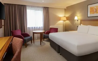 a hotel room with a bed and a table and chairs at Cambridge Belfry Hotel & Spa in Cambridge
