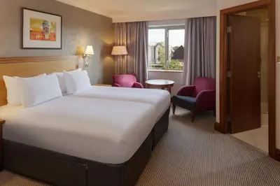 a hotel room with a large bed and a chair at Cambridge Belfry Hotel & Spa in Cambridge