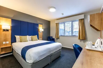 a hotel room with a large bed and a table at Days Inn London Stansted Airport in Stansted Mountfitchet
