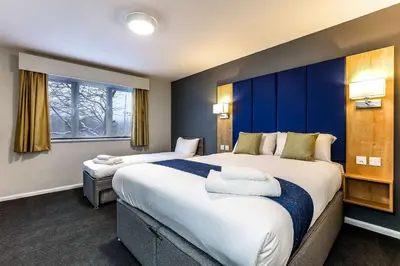 a hotel room with two beds and a window at Days Inn London Stansted Airport in Stansted Mountfitchet