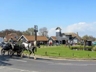 a horse pulling a carriage down a street at Ogilvie Lodge Apartment in Thorpeness