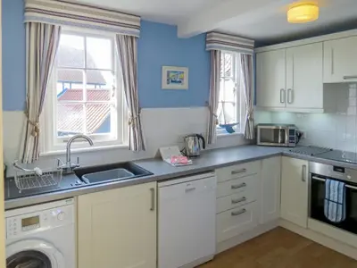 a kitchen with a sink and a washing machine at Ogilvie Lodge Apartment in Thorpeness