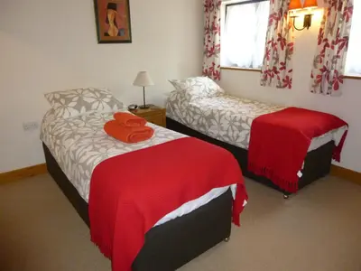 a bedroom with two beds with red sheets and a window at Golden Cross in Mendham
