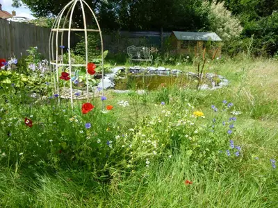 a garden with flowers and a bird cage and a pond at Golden Cross in Mendham