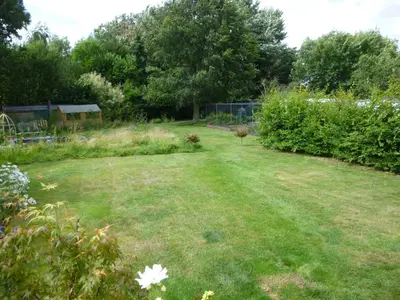 a garden with a large lawn and some bushes at Golden Cross in Mendham