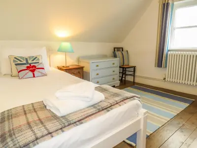 a bedroom with a bed and a dresser and a window at Thimble Cottage - Aldeburgh Coastal Cottages in Aldeburgh