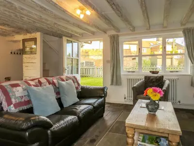 a living room with a leather couch and a table at Thimble Cottage - Aldeburgh Coastal Cottages in Aldeburgh