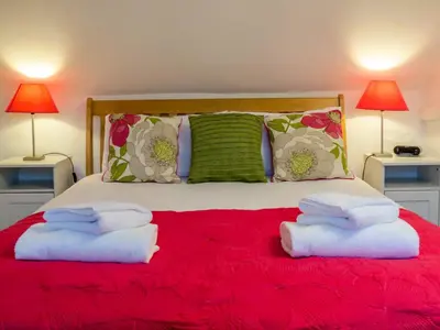 a bedroom with two towels on a red bed at Thimble Cottage - Aldeburgh Coastal Cottages in Aldeburgh