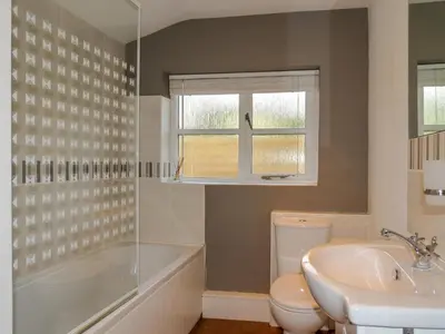 a bathroom with a tub and a toilet and a sink at Thimble Cottage - Aldeburgh Coastal Cottages in Aldeburgh