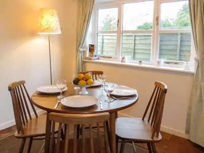 a dining room table with chairs and a window at Thimble Cottage - Aldeburgh Coastal Cottages in Aldeburgh