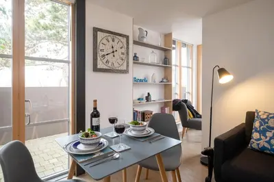 a living room with a table and a clock on the wall at Boat Lake in Thorpeness