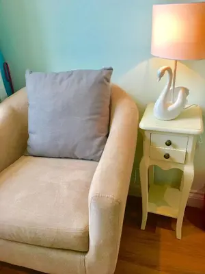 a chair with a pillow next to a table with a lamp at Angel's (station accommodation) in Cambridge