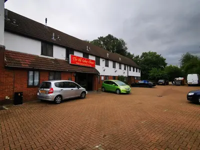 two cars parked in a parking lot in front of a building at The Oasis Hotel in Harlow