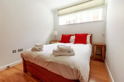 a bedroom with a bed with red pillows and a window at Stones Throw in Aldeburgh