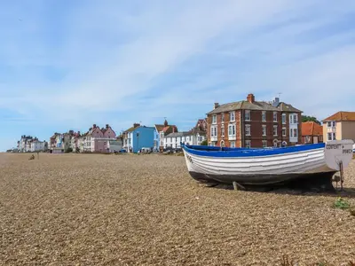 a boat on the beach with houses in the background at Stones Throw in Aldeburgh