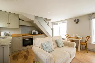 a living room with a couch and a kitchen at The Old Custom House in Aldeburgh