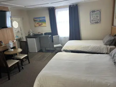 a hotel room with two beds and a table and a kitchen at Royal Albion Walton in Walton-on-the-Naze
