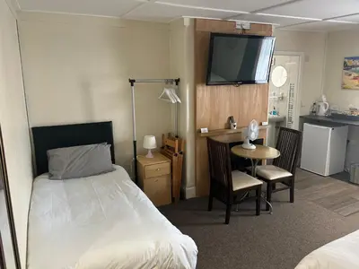 a bedroom with a bed and a table and a kitchen at Royal Albion Walton in Walton-on-the-Naze