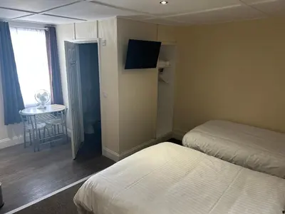 a room with two beds and a table and a window at Royal Albion Walton in Walton-on-the-Naze