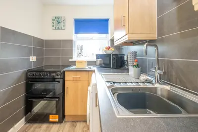 a kitchen with a sink and a stove at 17 Britten Close - Aldeburgh Coastal Cottages in Aldeburgh