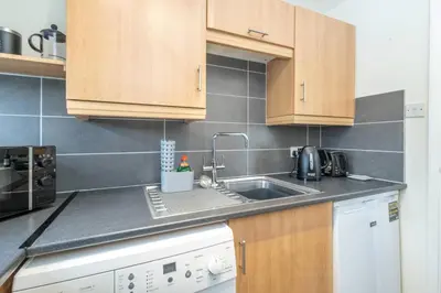 a kitchen with wooden cabinets and a sink at 17 Britten Close - Aldeburgh Coastal Cottages in Aldeburgh