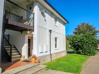 a white house with a staircase and a balcony at 17 Britten Close - Aldeburgh Coastal Cottages in Aldeburgh