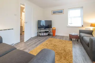a living room with a couch and a tv at 17 Britten Close - Aldeburgh Coastal Cottages in Aldeburgh