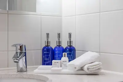 a bathroom counter with two blue bottles and towels at Radisson Blu Hotel London Stansted Airport in Stansted Mountfitchet
