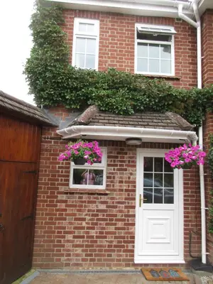 a brick house with a white door and pink flowers at Shear Annexe Flat in Cambridge
