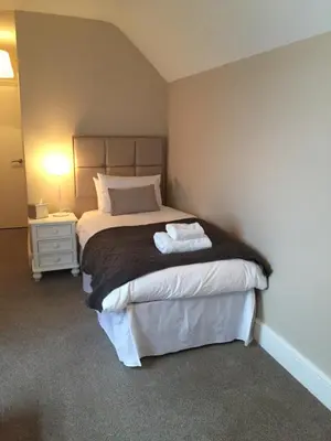 a bedroom with a bed and a night stand with a lamp at The Swan Hotel Bar and Grill in Maldon
