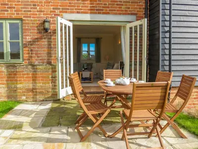 a wooden table and chairs on a patio at Sanderling Home in Aldeburgh