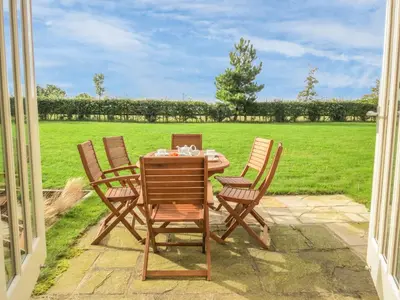 a table and chairs with a view of a field at Sanderling Home in Aldeburgh