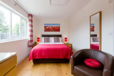 a bedroom with a red bed and a chair at 1 Suffolk Cottage, Knodishall - Aldeburgh Coastal Cottages in Aldeburgh