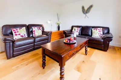 a living room with leather couches and a coffee table at 1 Suffolk Cottage, Knodishall - Aldeburgh Coastal Cottages in Aldeburgh