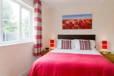 a bedroom with a bed with a red blanket at 1 Suffolk Cottage, Knodishall - Aldeburgh Coastal Cottages in Aldeburgh