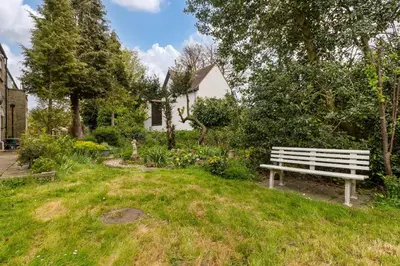a park bench sitting in the grass in front of a house at Shelford Lodge in Cambridge