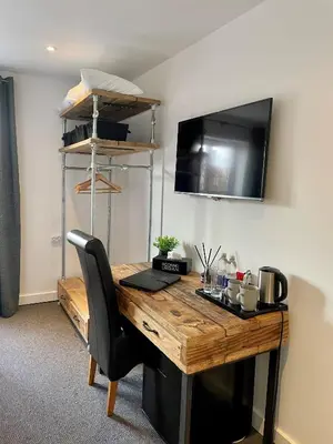 a desk with a computer and a television on a wall at Booking Urban at Stisted in Braintree