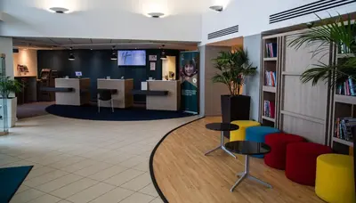 an office with a library with chairs and tables at Holiday Inn Express London Stansted Airport by IHG in Stansted Mountfitchet